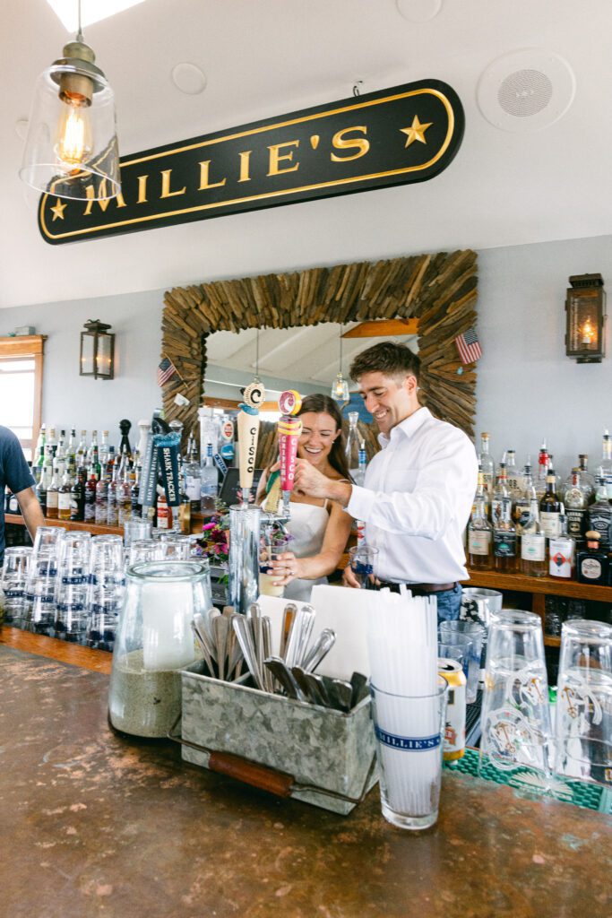 Bride and groom pour themselves a beer at Millie's Nantucket after beach elopement.