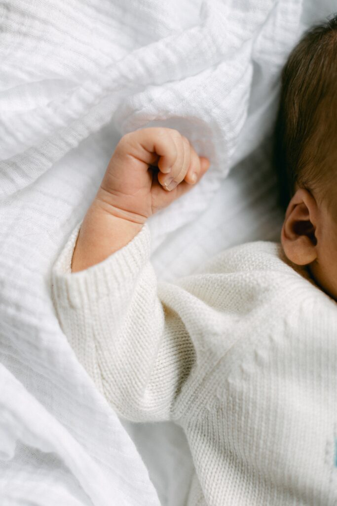 Baby's arm and hand in ivory sweater.