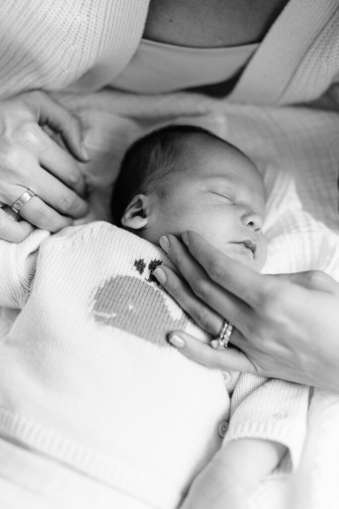 Black and white image of mom gently touching her newborn baby's cheek.