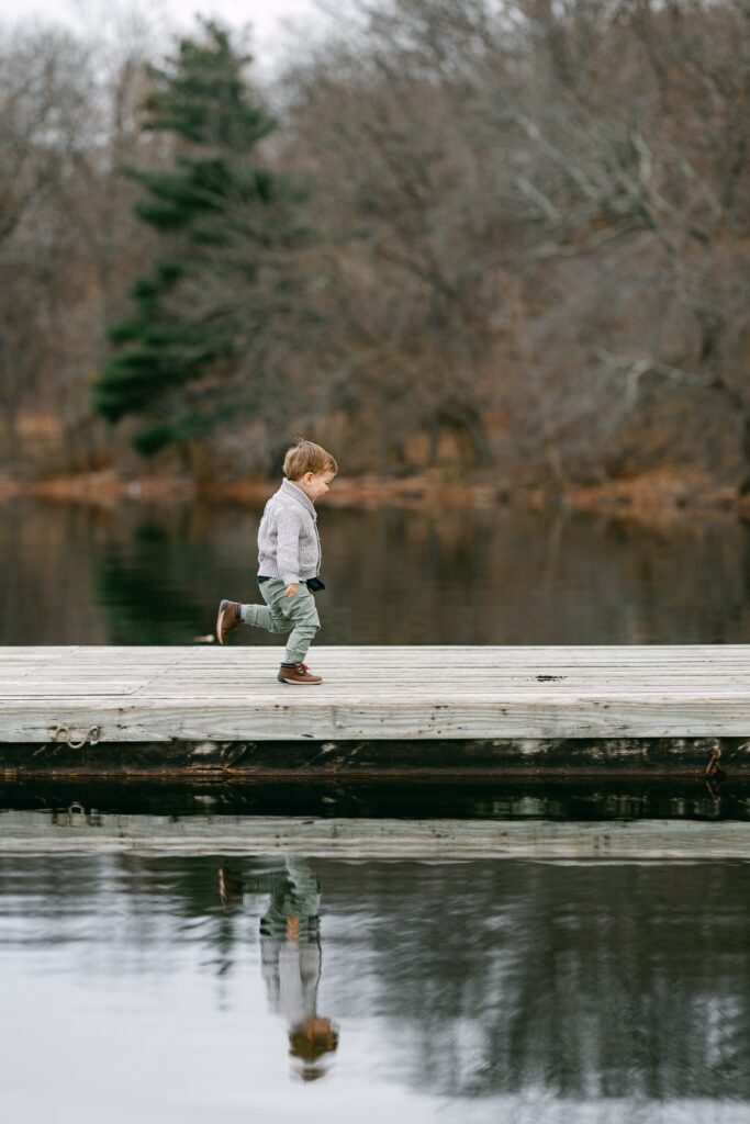 Toddler boy running on dock shot from afar. 