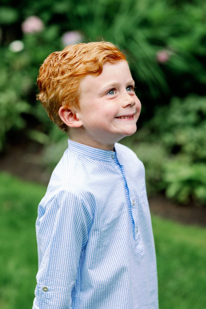 Red-head boy in striped blue shirt smiling.