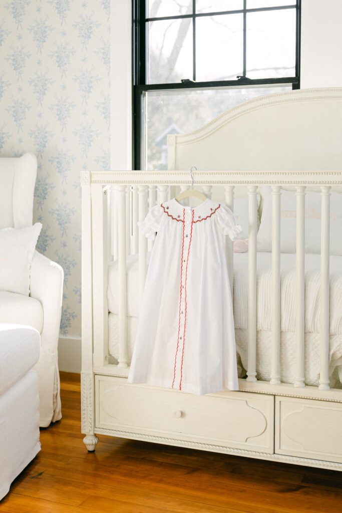 Crib shot with baby gown hanging off the railing. 