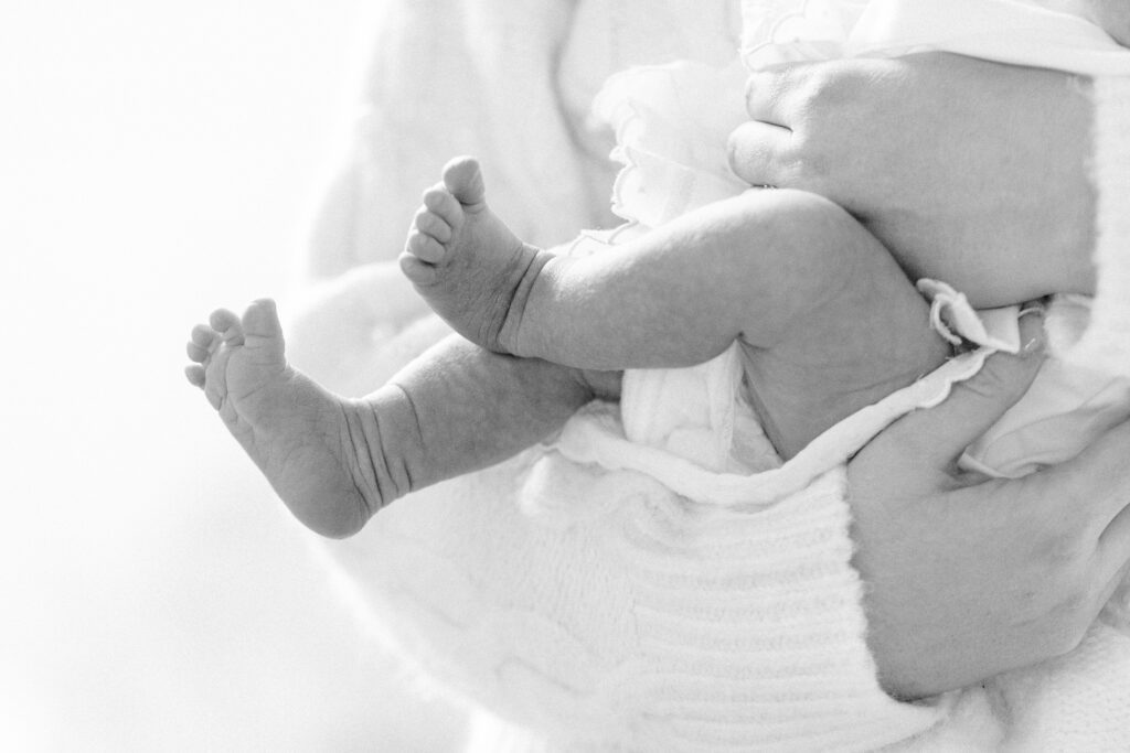 Close-up of baby legs and feet in mom's arms. 