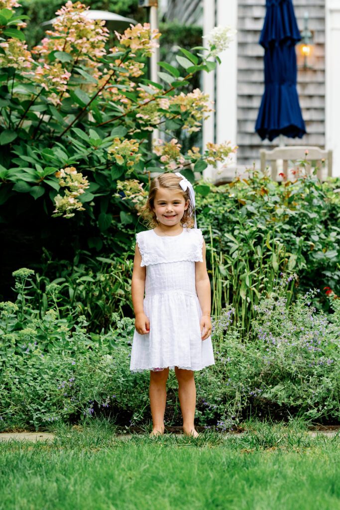 young girl in white dress in backyard