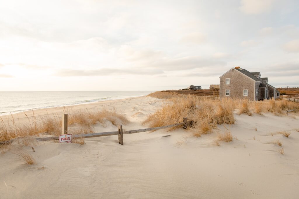 A peaceful scene at a quiet Nantucket beach on a winter's day. Two houses can be seen, as well as a Private Property sign that has become buried in the sand over time.
