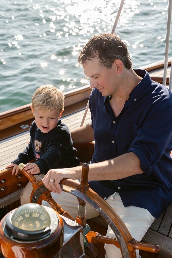A father and son are steering The Blue Peter Yacht sailboat on Nantucket together. 