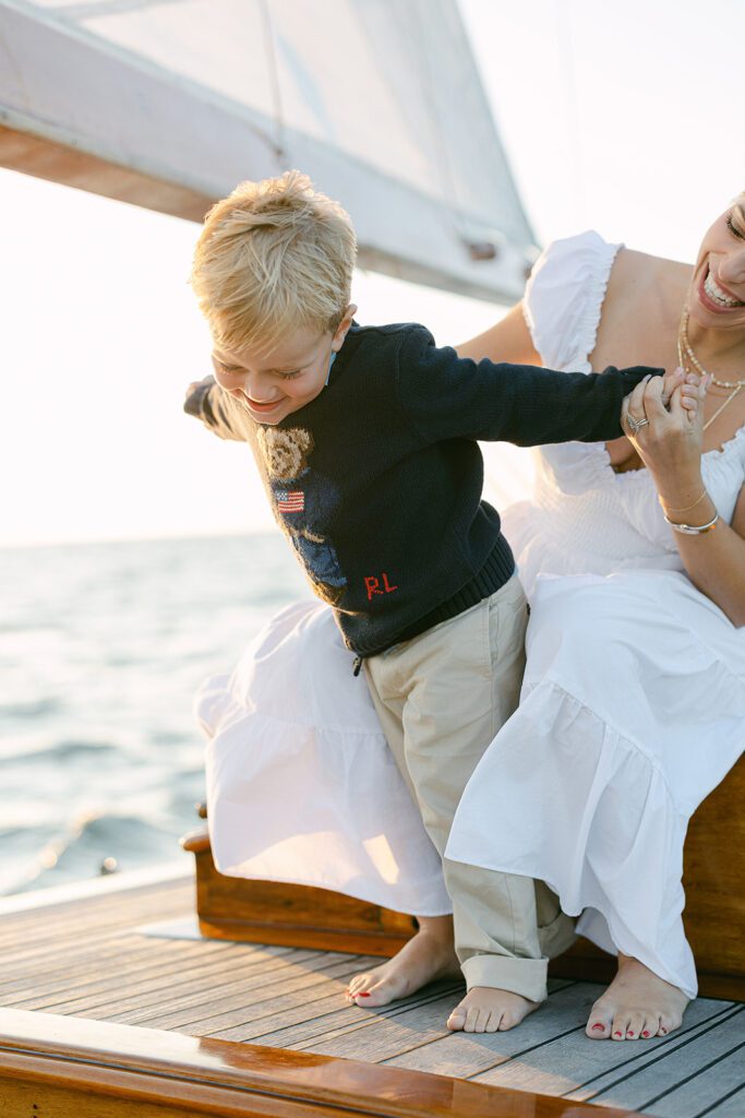 A mom and her son are on the deck of the The Blue Peter Yacht sailboat on Nantucket, goofing around with one another. 