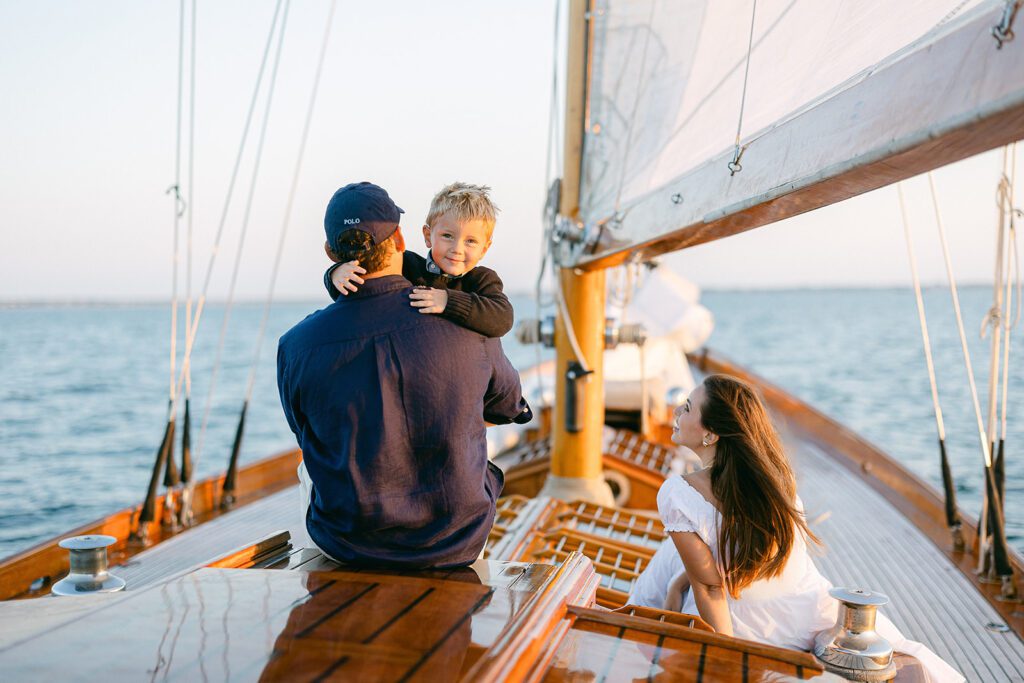 A couple an their son are sitting on the deck of he Blue Peter Yacht sailboat on Nantucket, enjoying the view and each other's company. 