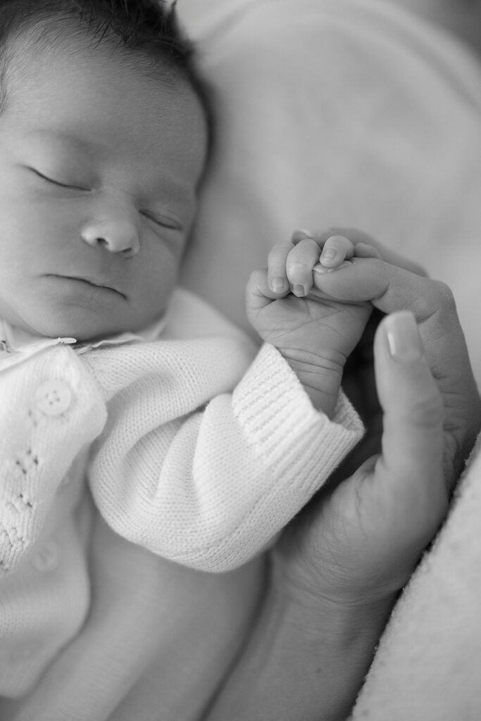 A sleeping newborn is clutching her mother's index finger with her tiny hand at home in the Connecticut suburbs. 