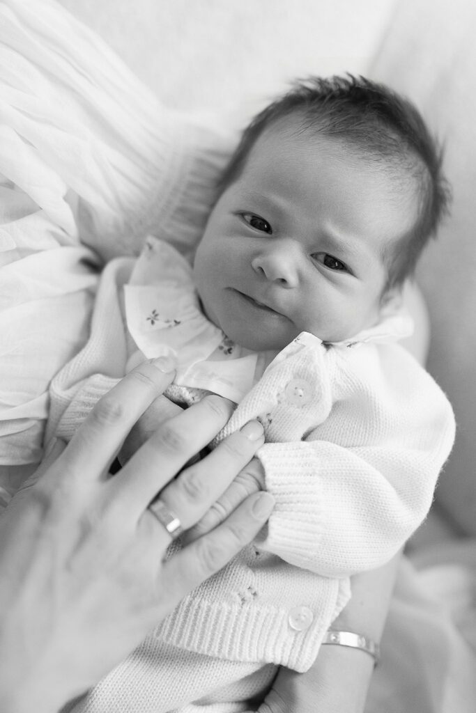 A newborn baby girl is looking off to the side while mom is holding her in their home in the Connecticut suburbs. 