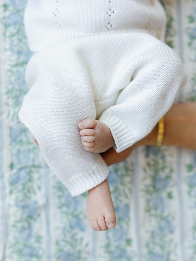 A newborn baby girl's toes are curled up as she lays on a floral sheet in the nursery of her home in the suburbs of Connecticut. 